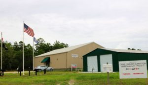 Two metal museum buildings with an American flag in front.