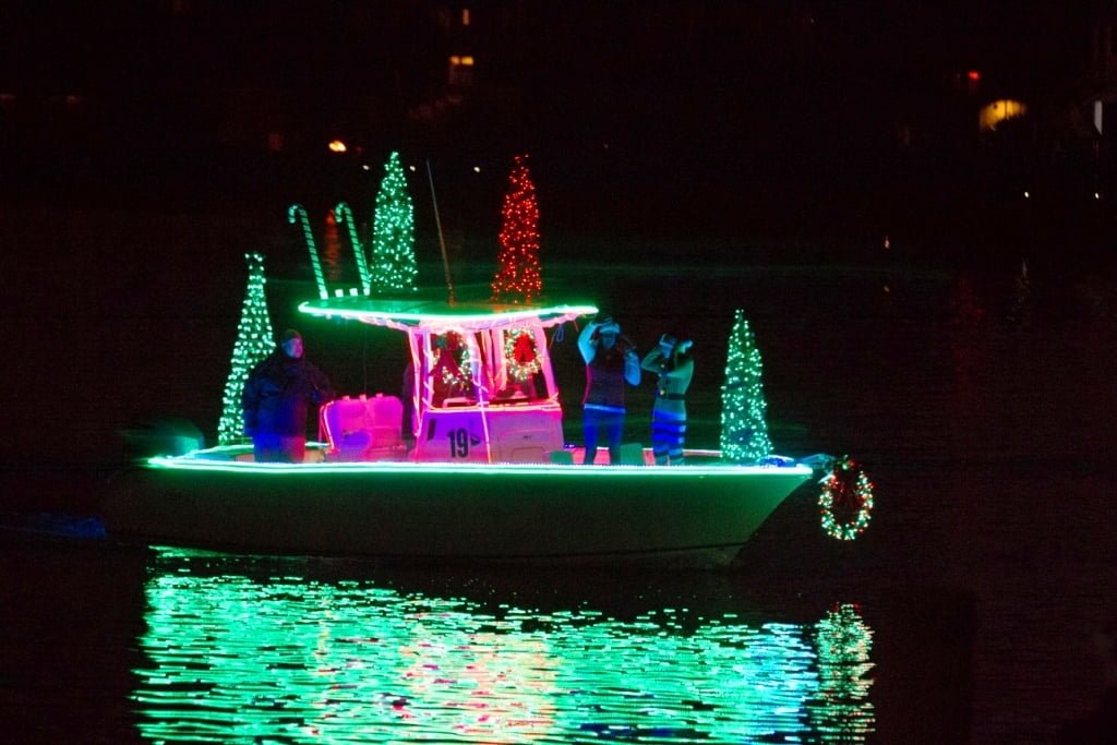 Boat decorated with green Christmas lights floats in the water