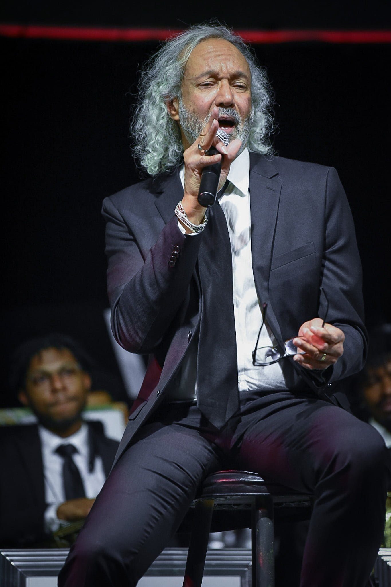 Darryl Tookes in a gray suit sings into a microphone