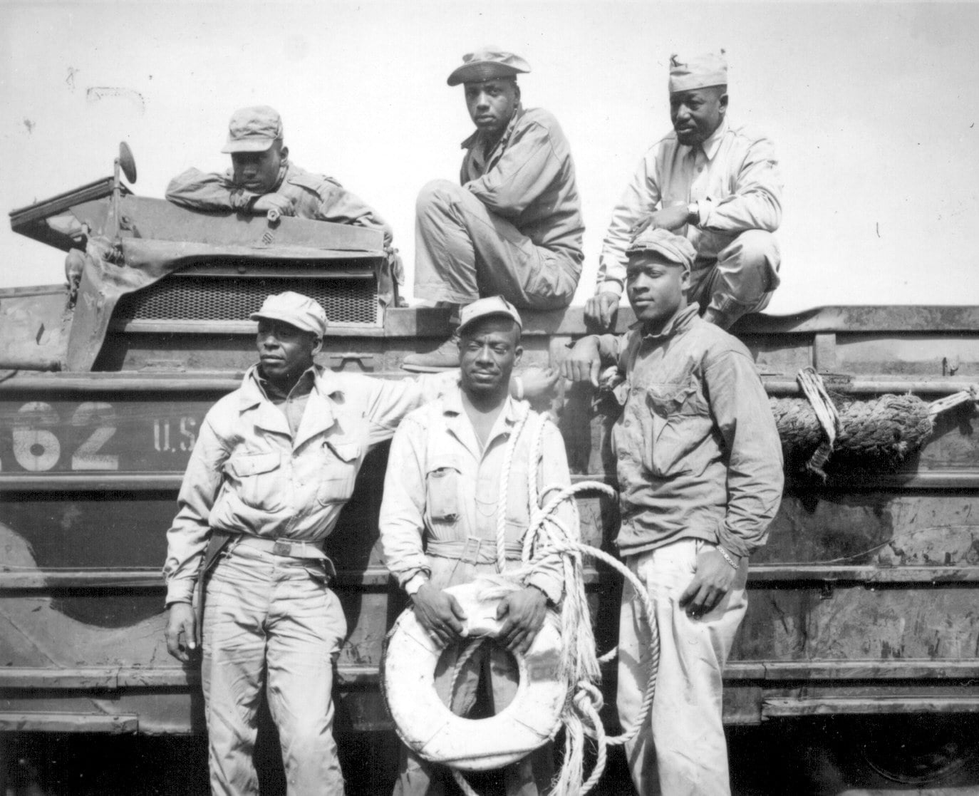 Six African American soldiers pose in front of a WWII DUKW