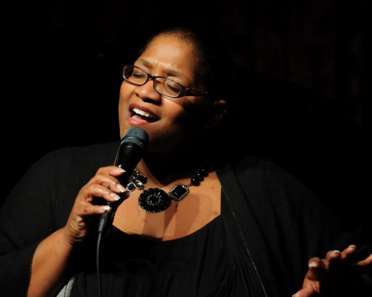 Avis Berry sings into a microphone while smiling