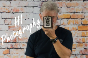 Man in a black shirt holding an antique camera in front of his face
