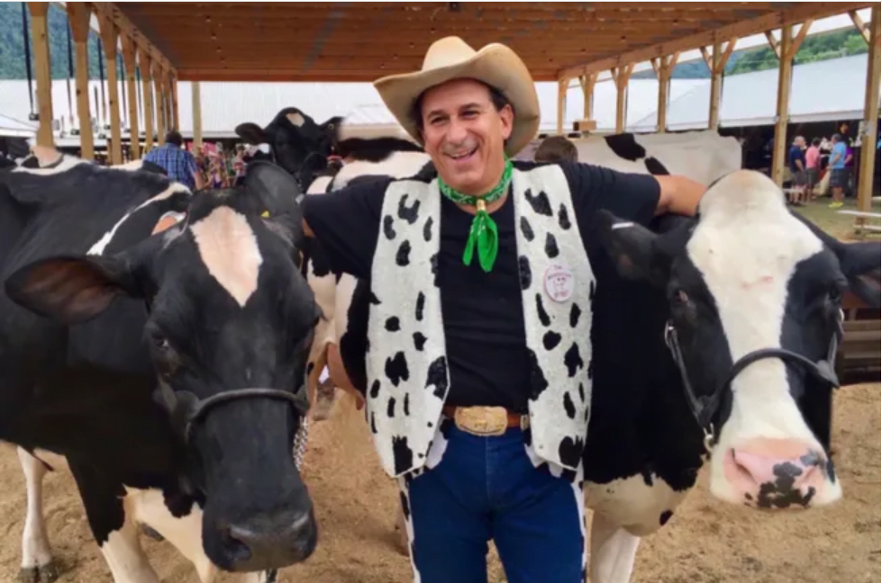 A man in a cowboy hat stands next to some cows