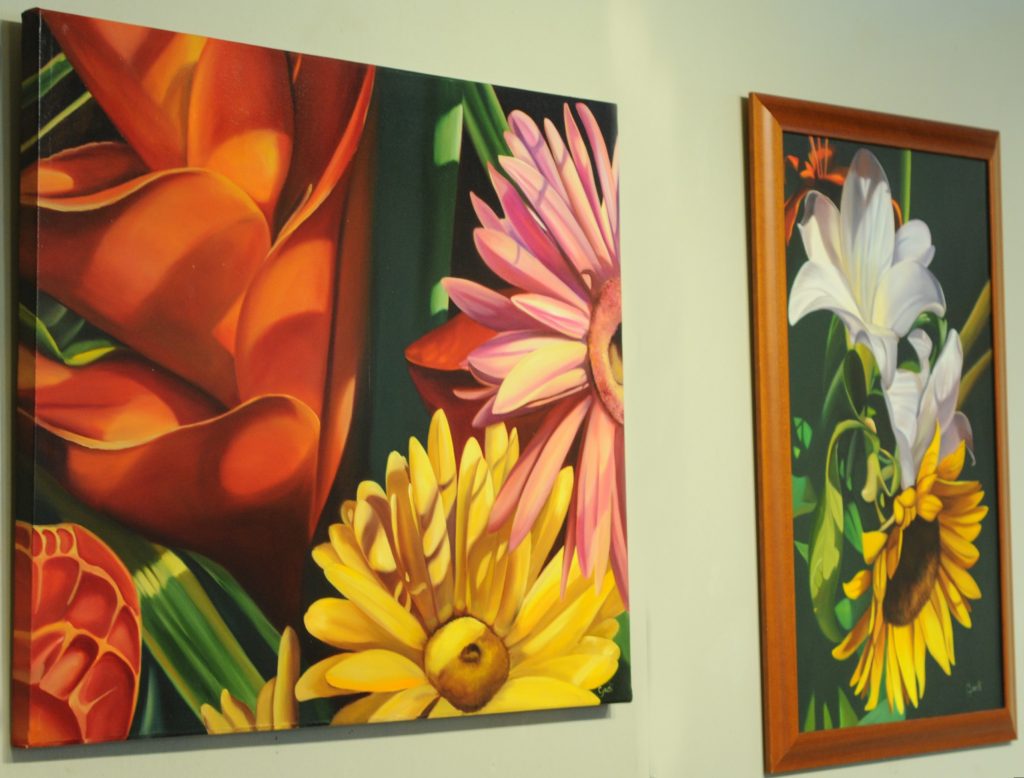 Two painting of colorful flowers hang on a wall