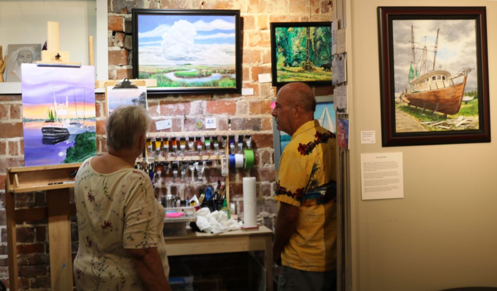 Two people stand chatting while looking at art work