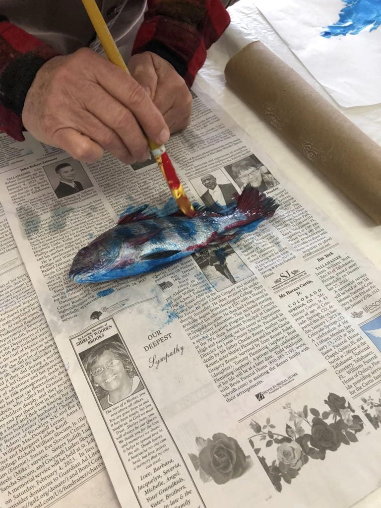 Hands of someone painting ink onto a fish