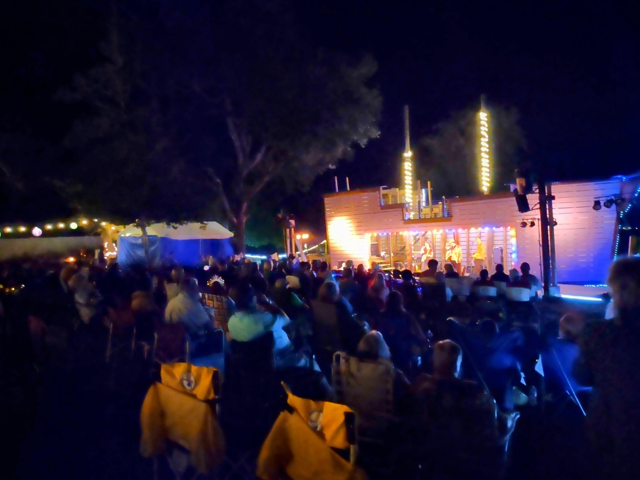 A crowd watches a performance on a pirate ship stage at night